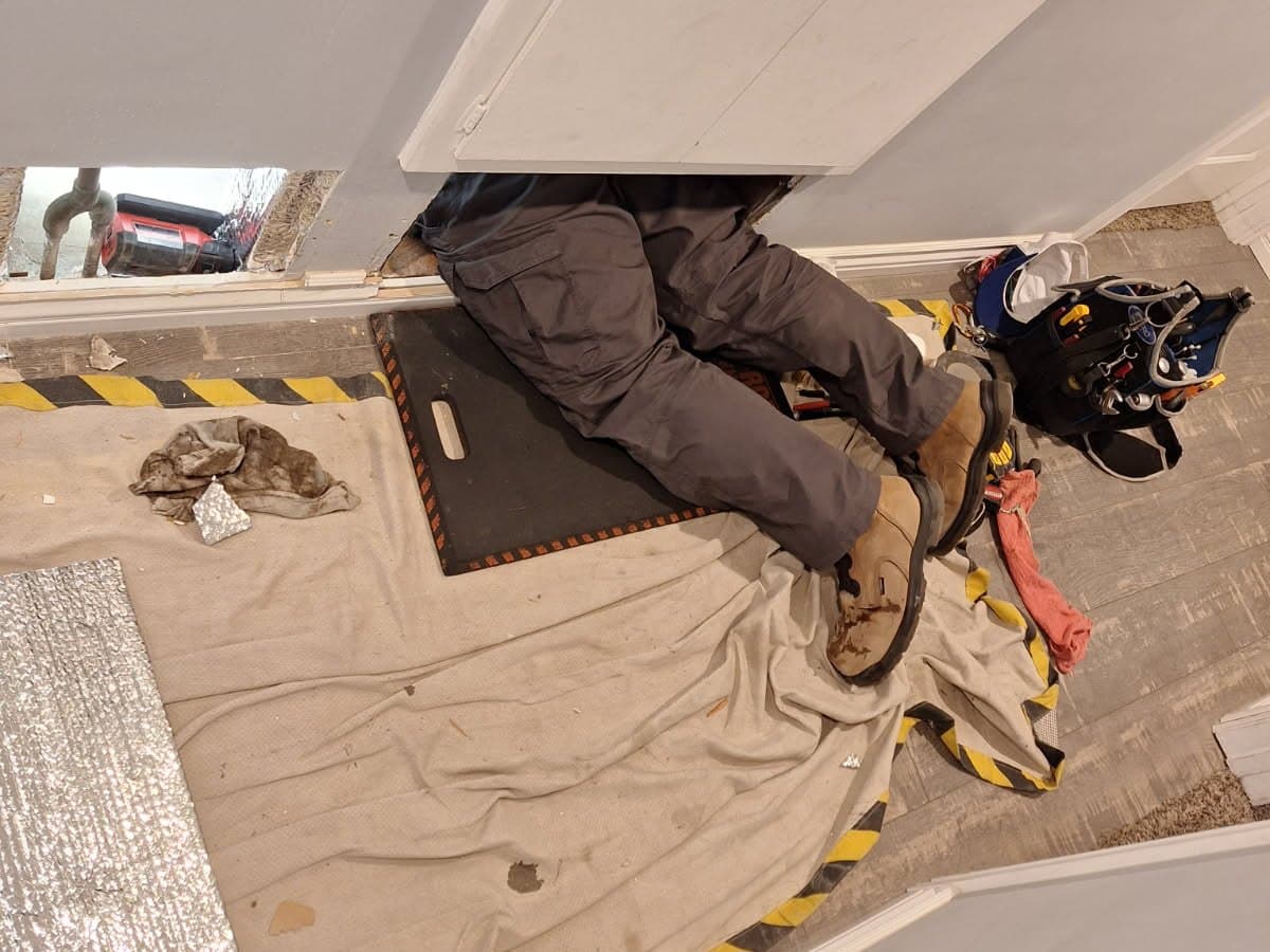 Technician working a tight crawlspace install